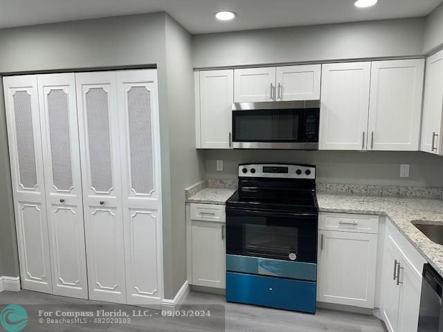 a kitchen with white cabinets and stainless steel appliances