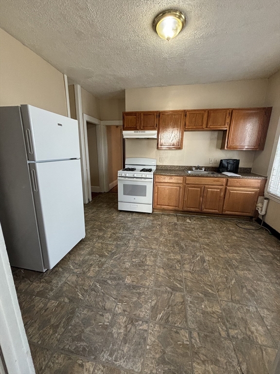 a kitchen with stainless steel appliances granite countertop a refrigerator a stove and a sink