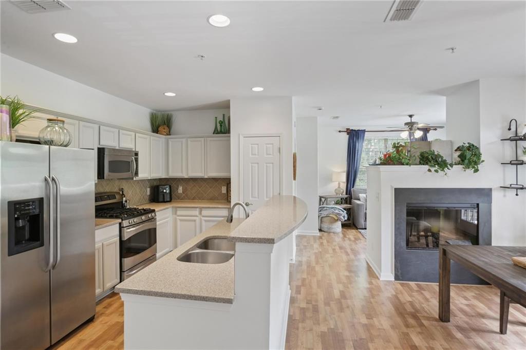 a kitchen with refrigerator a oven and a stove with wooden floor