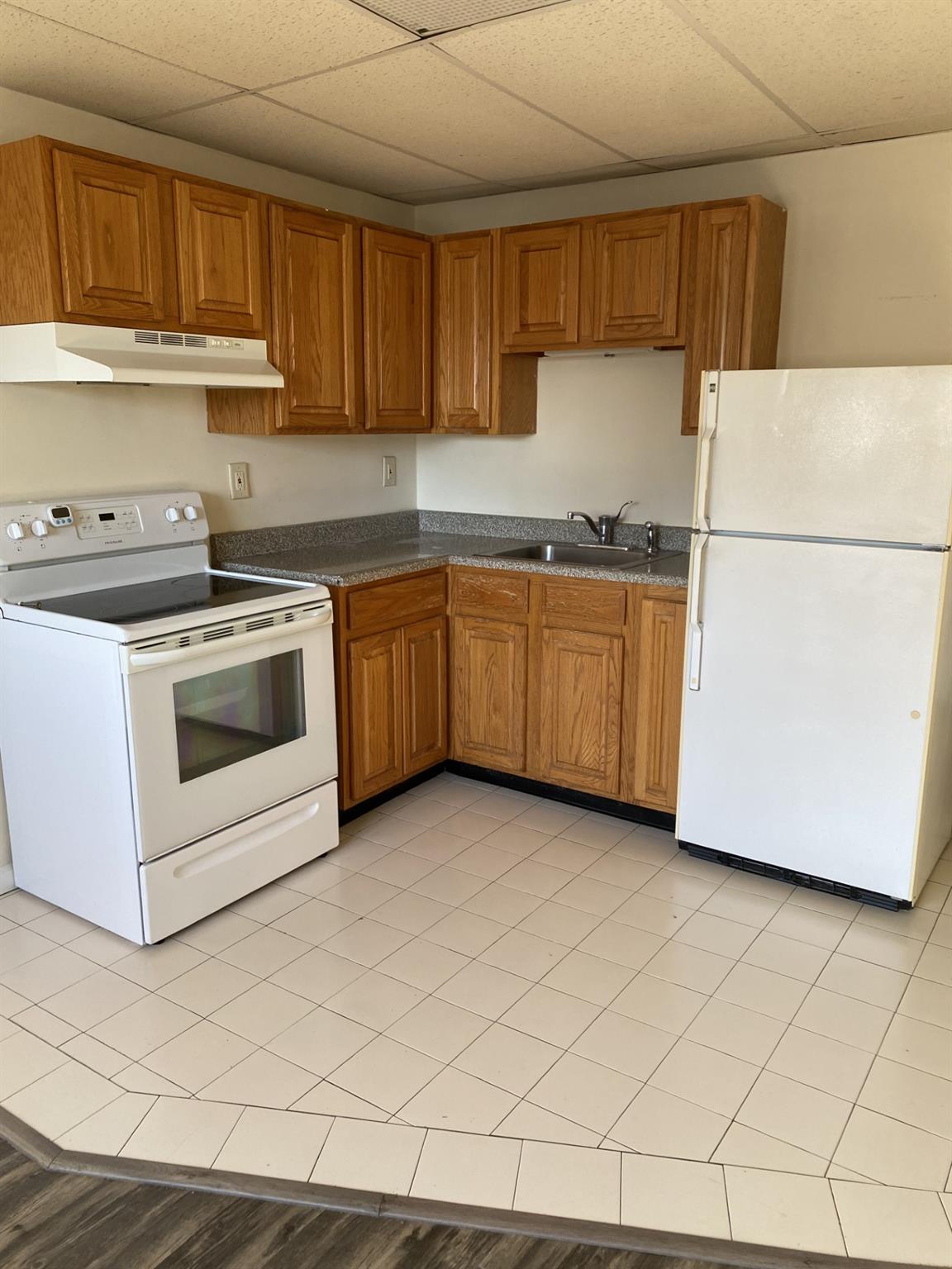 Kitchen with a paneled ceiling, sink, and white appliances