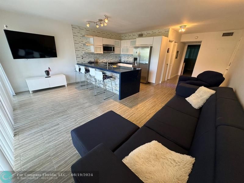 a living room with stainless steel appliances furniture and a flat screen tv