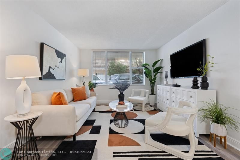 a living room with furniture a flat screen tv and a potted plant