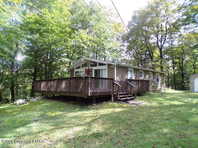 a view of a backyard with a large tree and a wooden deck