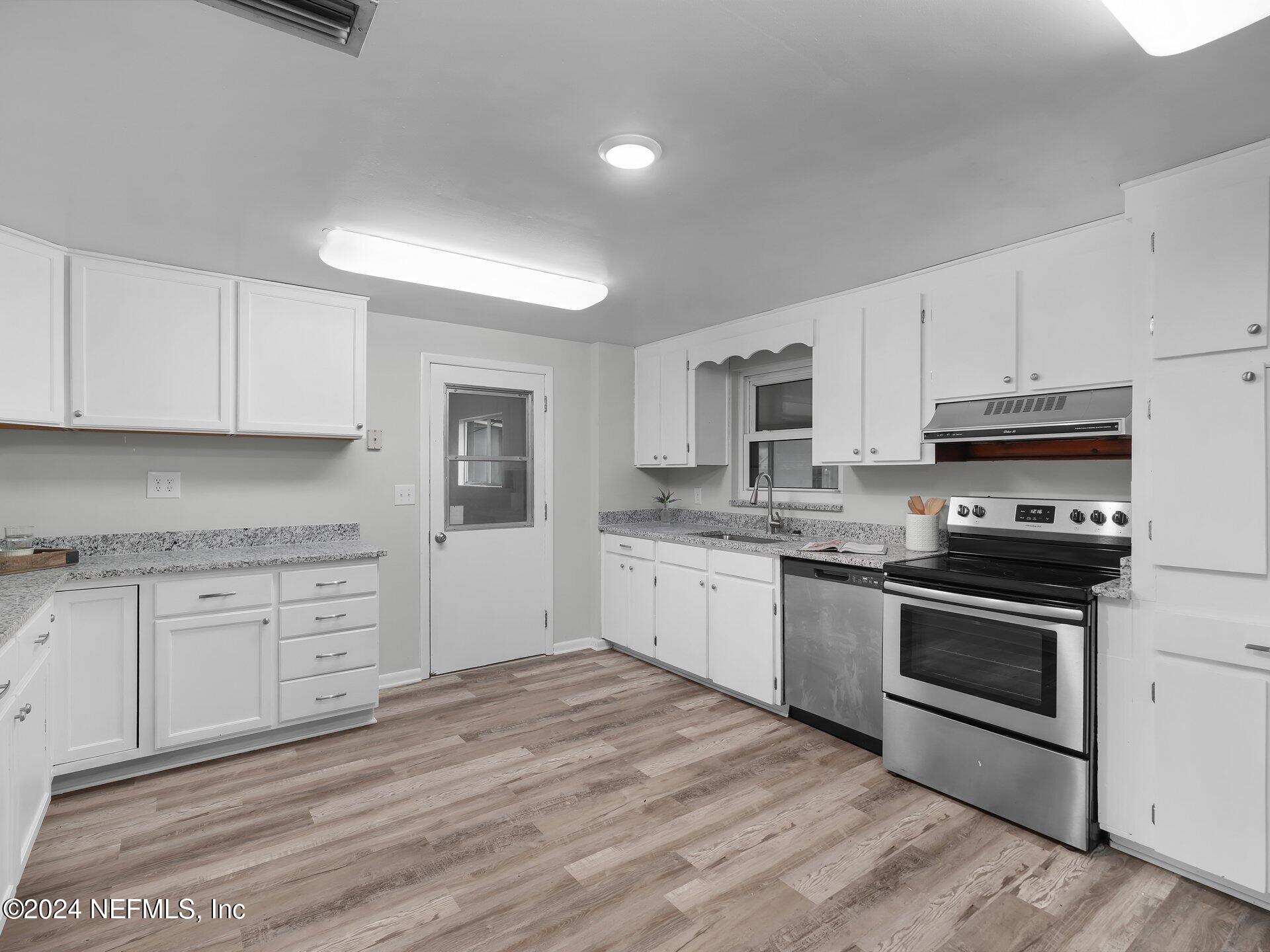 a kitchen with granite countertop white cabinets stainless steel appliances and a sink