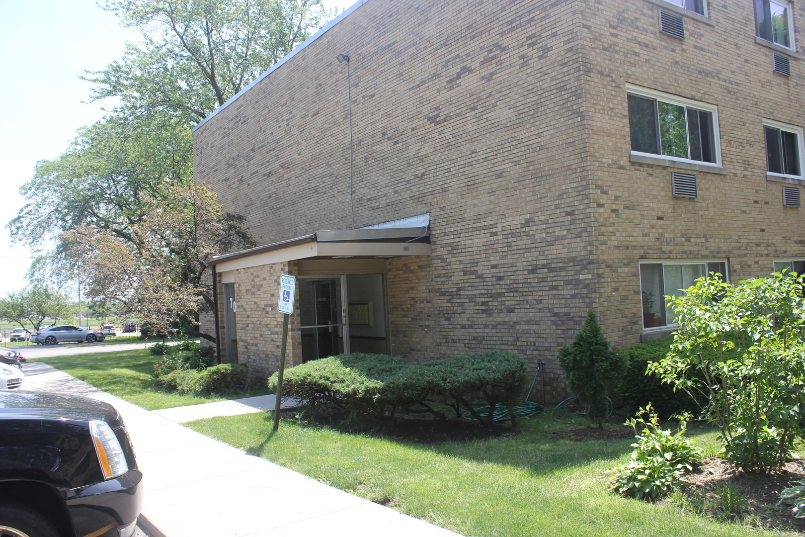 a brick house with a yard plants and large tree