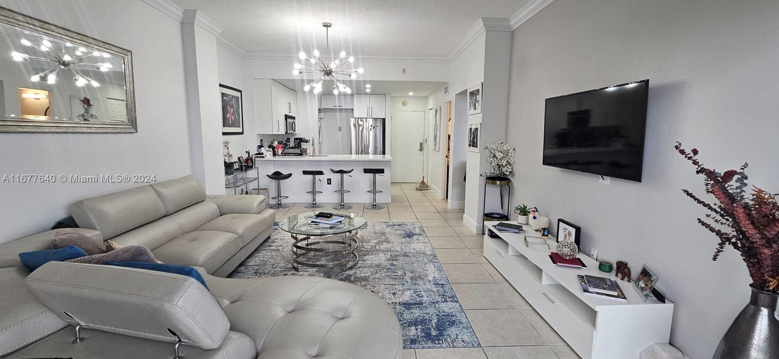 a living room with furniture a chandelier and a flat screen tv