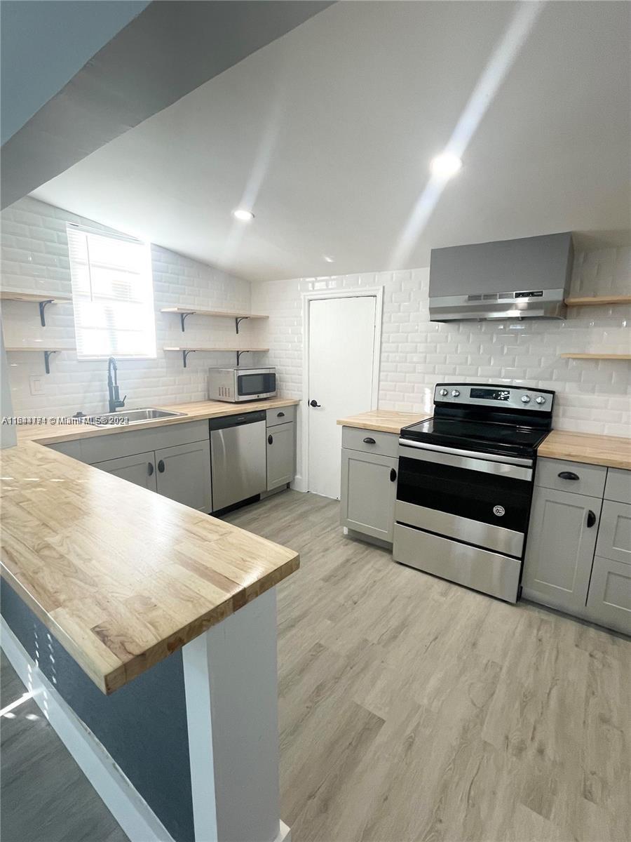 a kitchen with stainless steel appliances kitchen island granite countertop a refrigerator and a sink