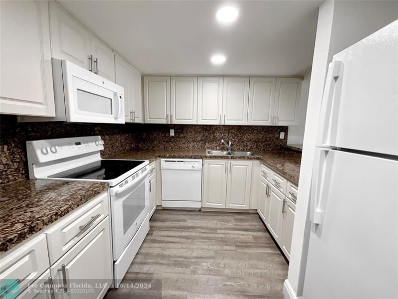 a kitchen with granite countertop a sink a counter top space and cabinets