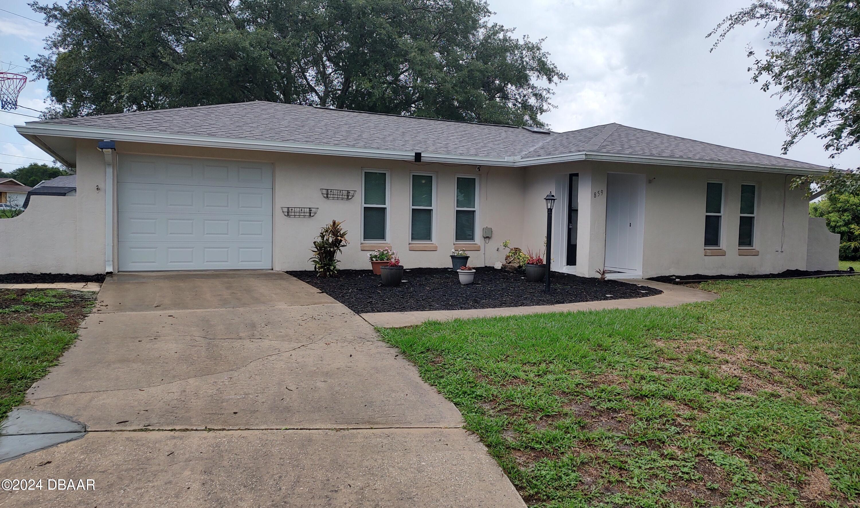 a front view of a house with a garden and trees