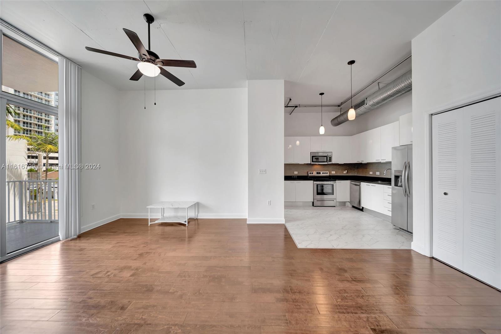 a view of an empty room with a window and wooden floor