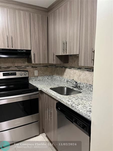 a kitchen with granite countertop a stove top oven cabinetry a sink and dishwasher