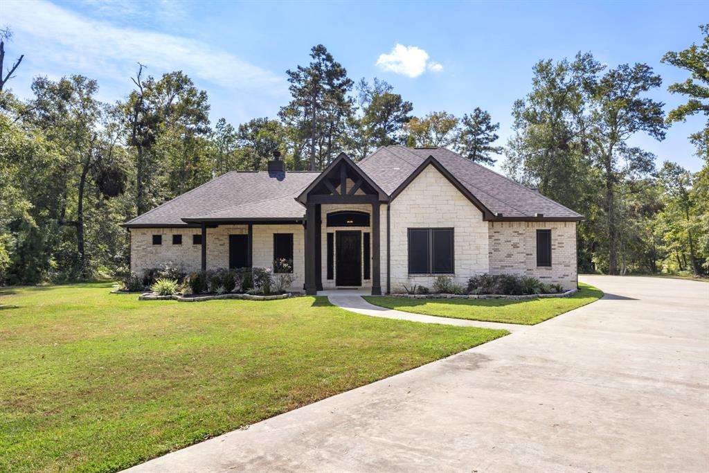 a front view of a house with a garden and trees