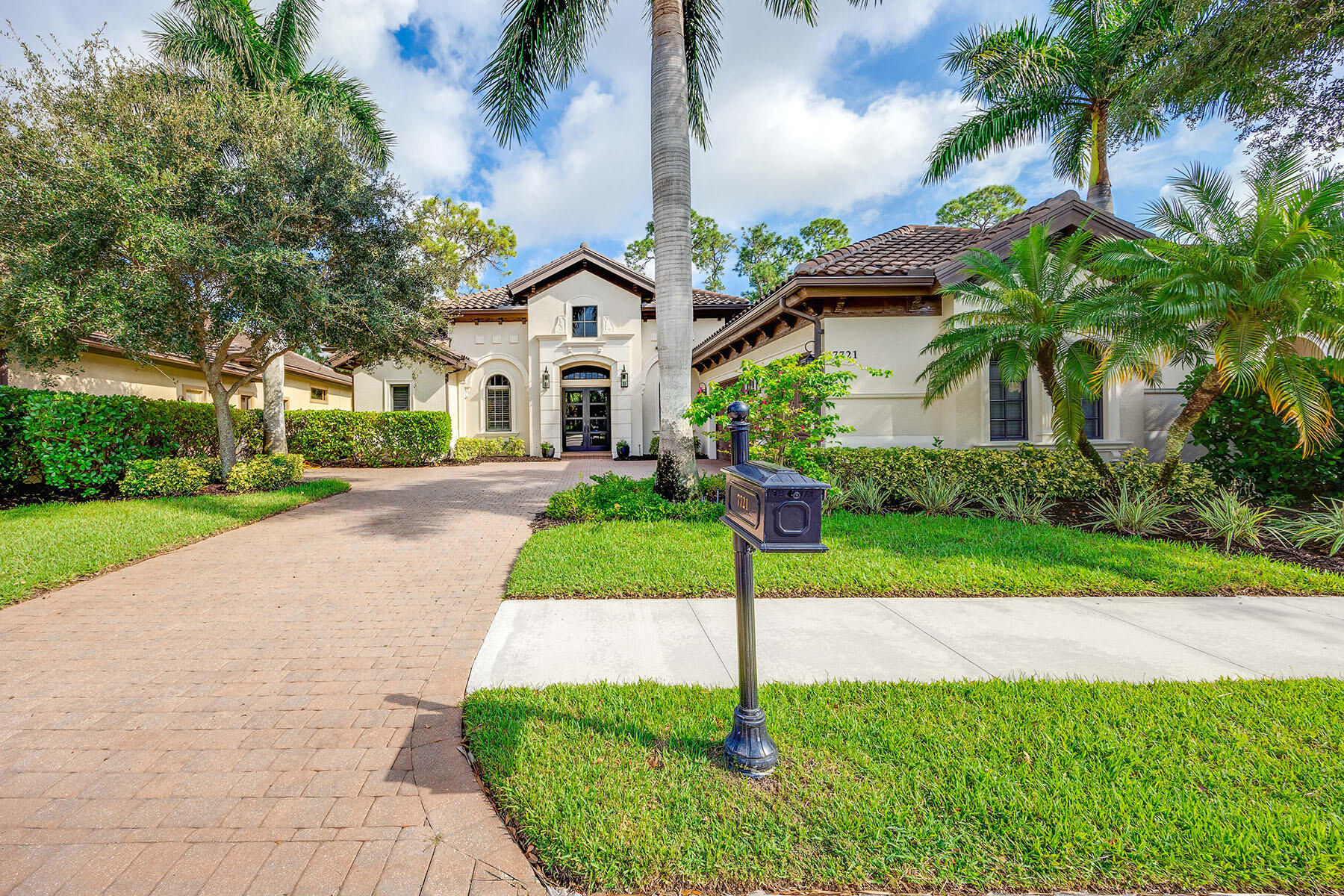 a front view of a house with a yard and palm trees