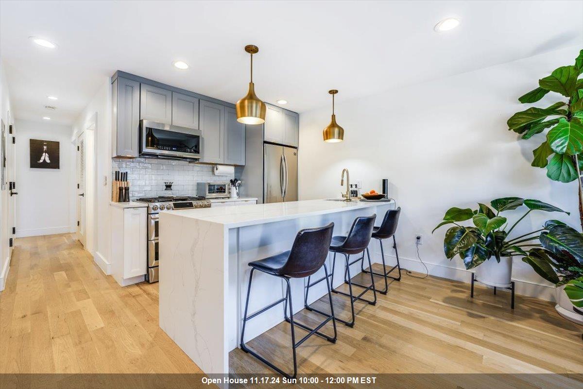 a living room with furniture a potted plant and kitchen view