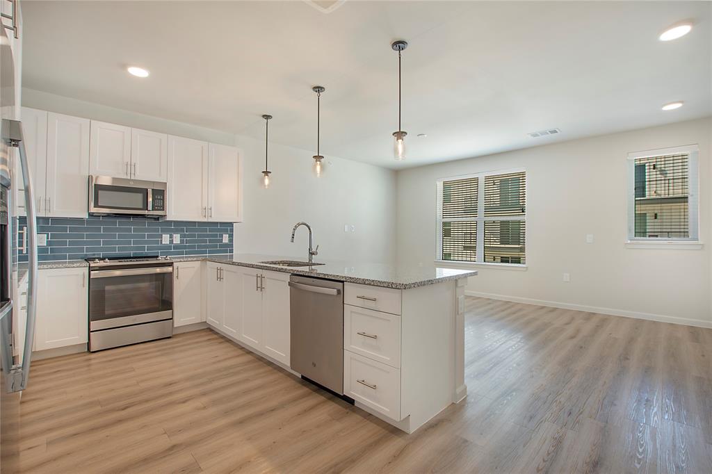 a kitchen with kitchen island granite countertop a sink cabinets and wooden floor