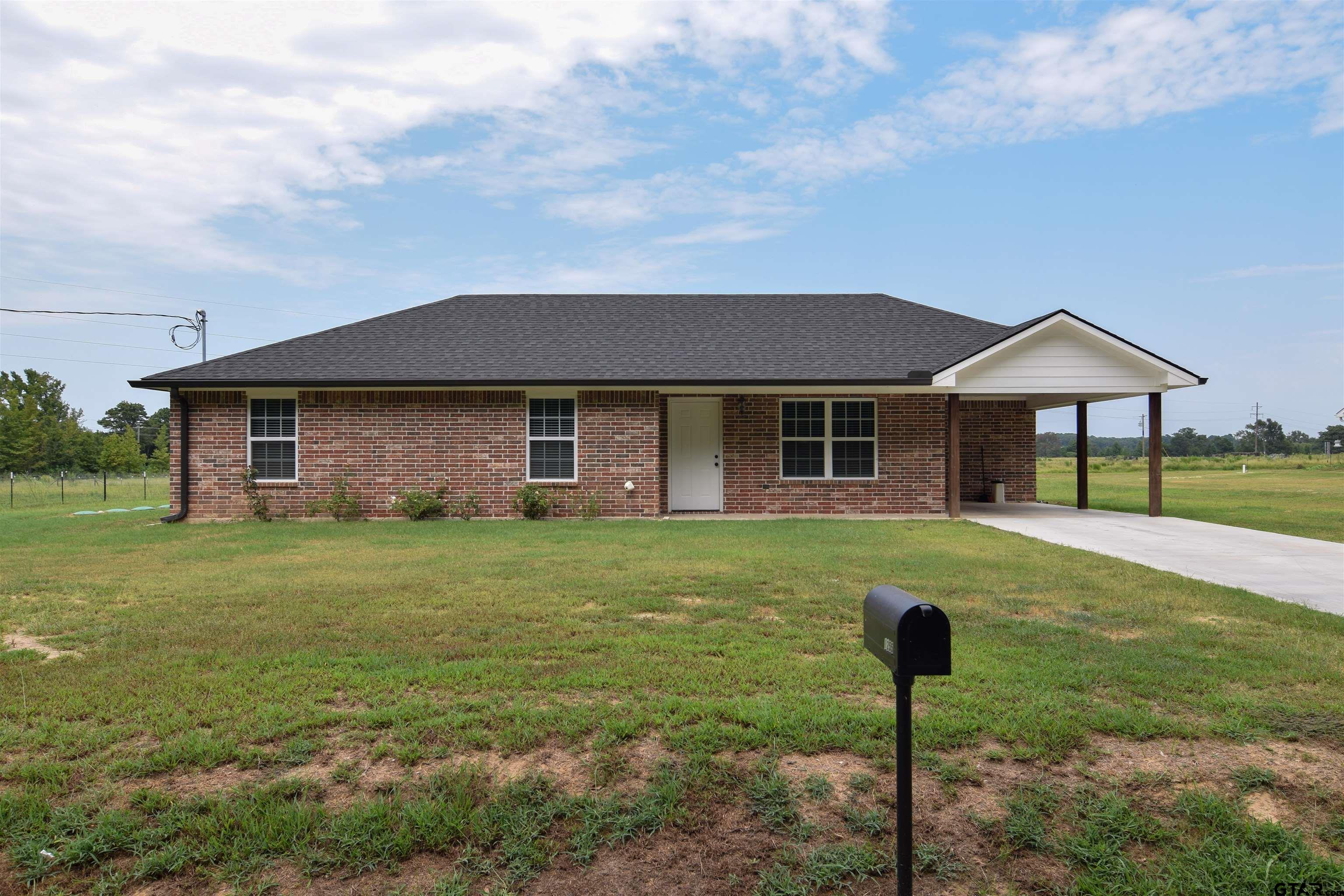 a front view of a house with a yard and trees