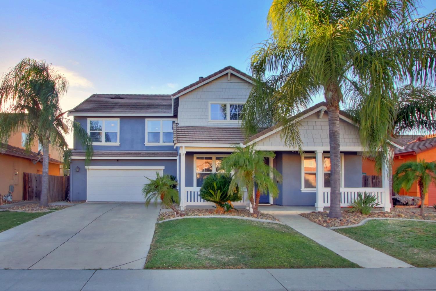 a front view of a house with a garden and palm trees