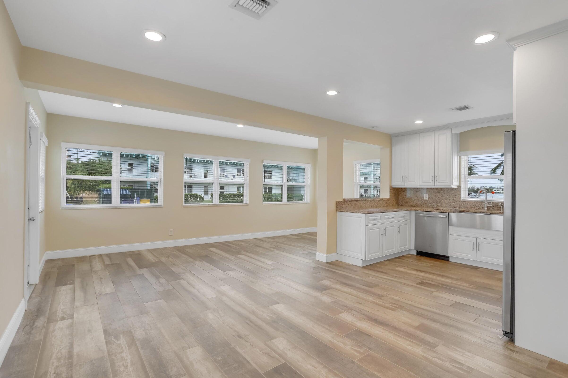 a large white kitchen with kitchen island wooden floors and white cabinets