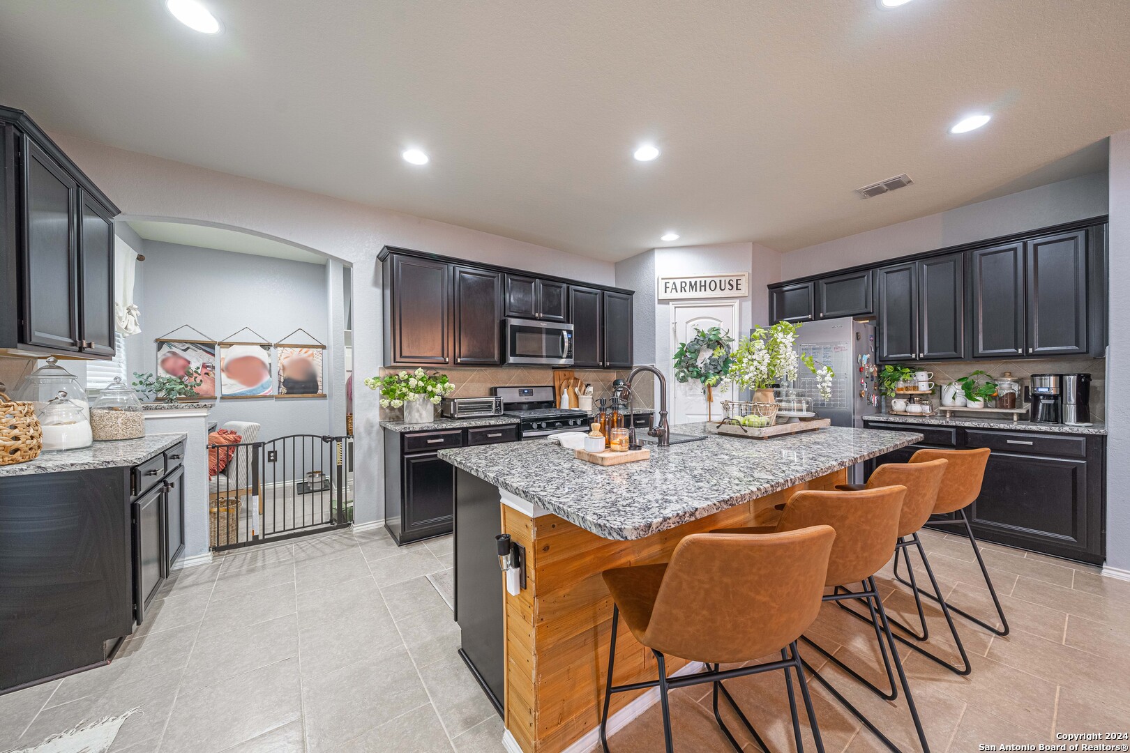 a kitchen with stainless steel appliances granite countertop table chairs sink refrigerator and cabinets