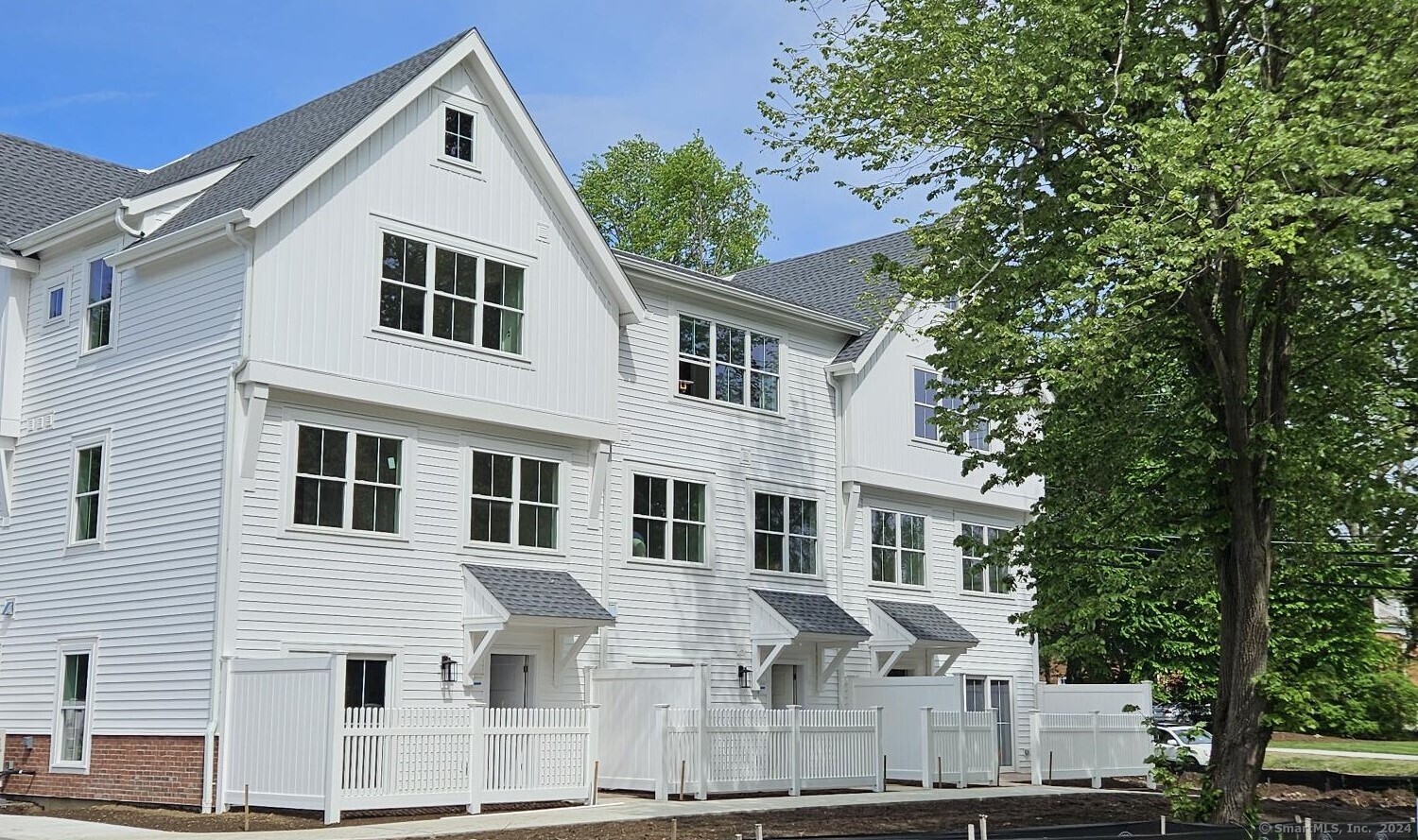 a view of a white house with large windows and a tree