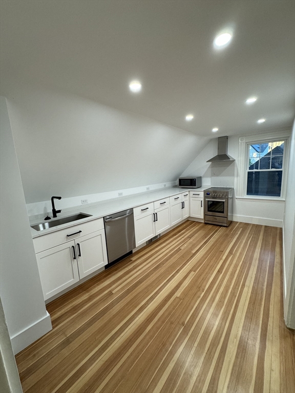 a kitchen with stainless steel appliances wooden floor and a stove top oven