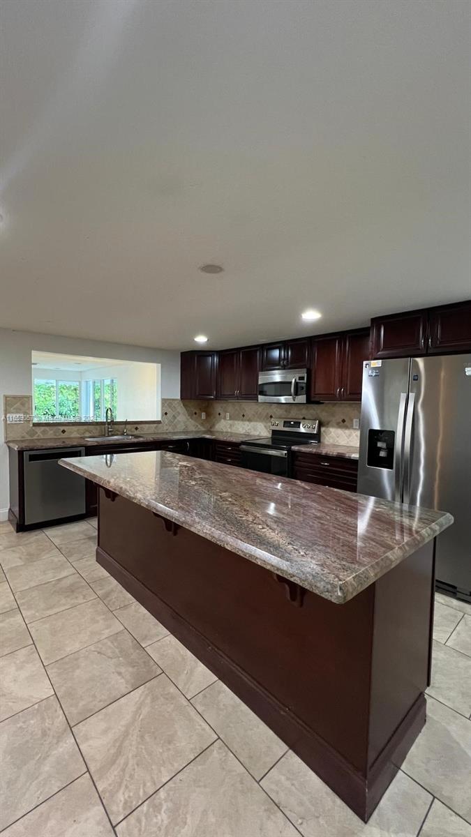 a large kitchen with kitchen island granite countertop a large counter top and a sink with granite countertops