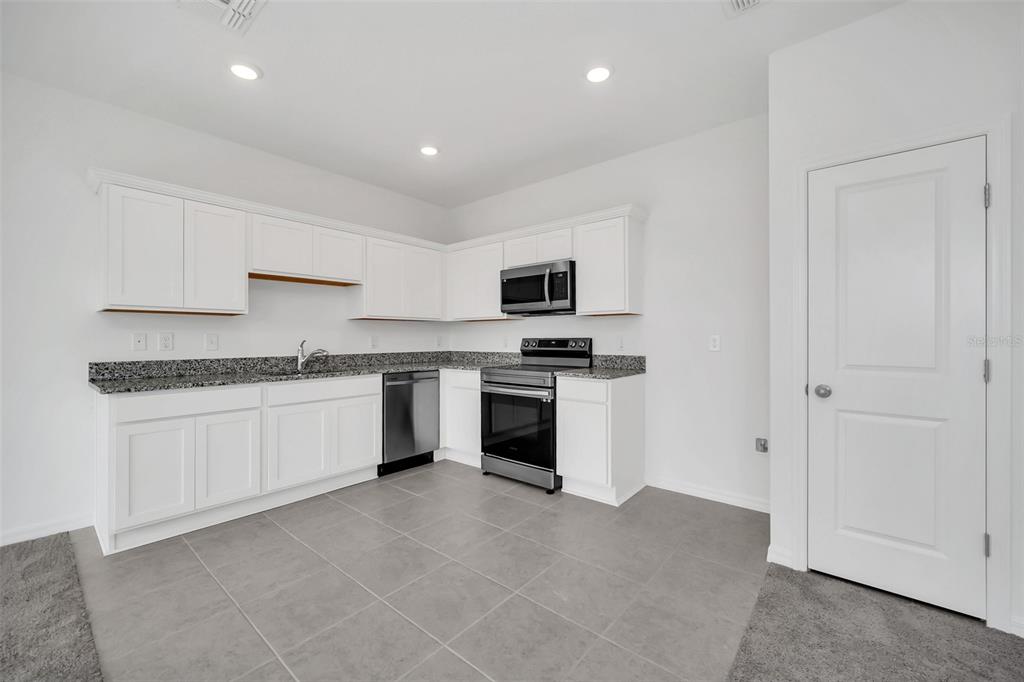 a kitchen with granite countertop white cabinets and stainless steel appliances