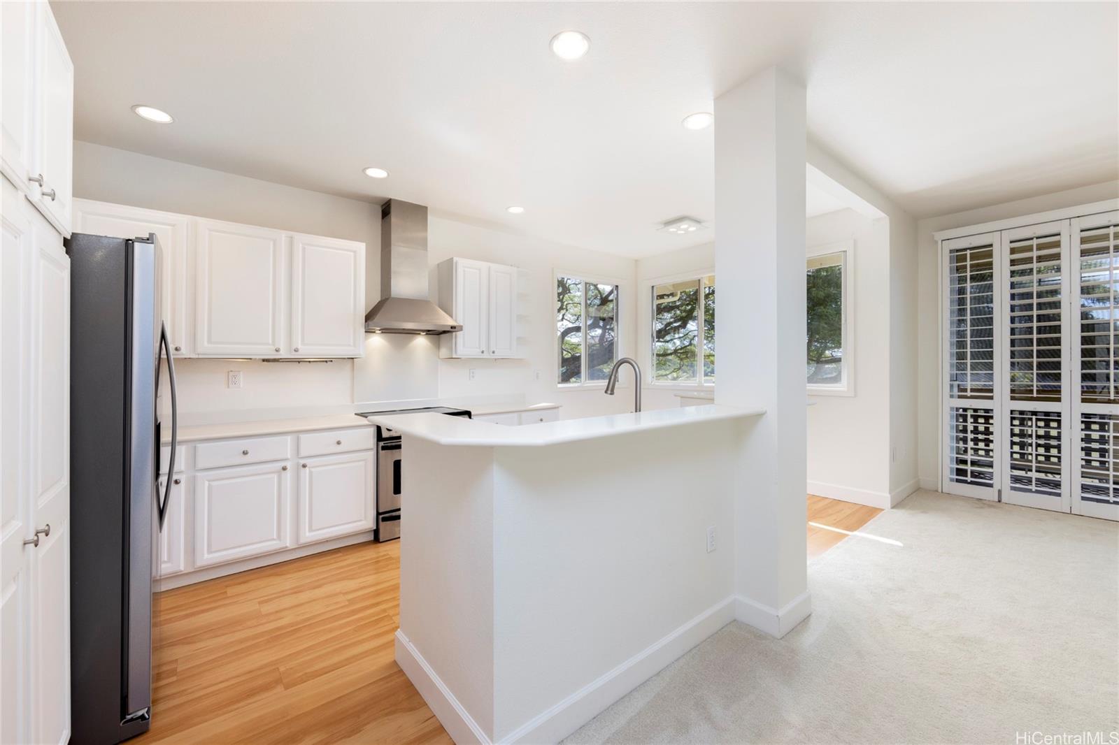 a kitchen with white cabinets and wooden floor