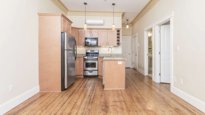 a kitchen with stainless steel appliances a refrigerator and wooden floor