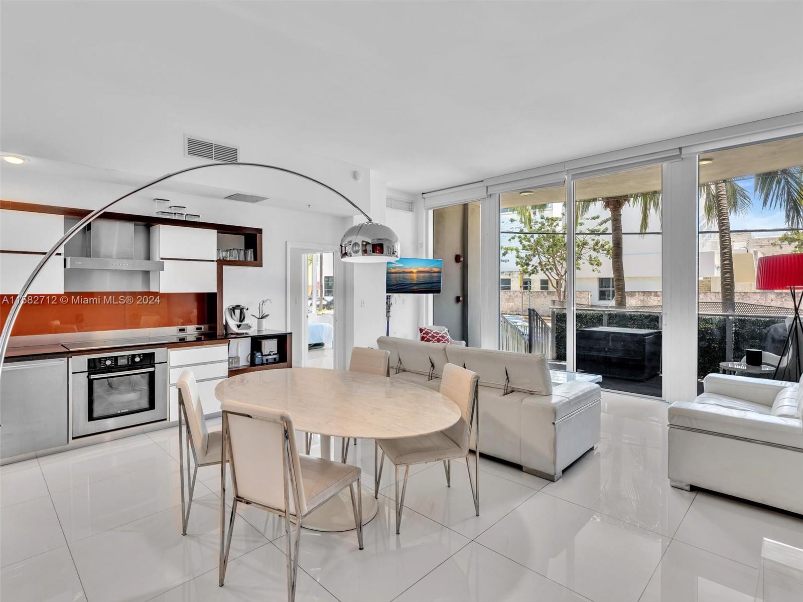 a living room with furniture a large window and kitchen view