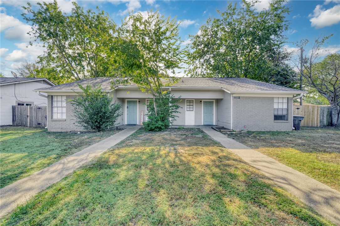 a view of a house with a yard and large tree