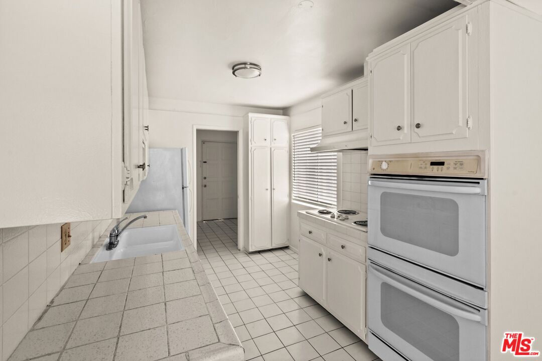 a kitchen with white cabinets and white appliances