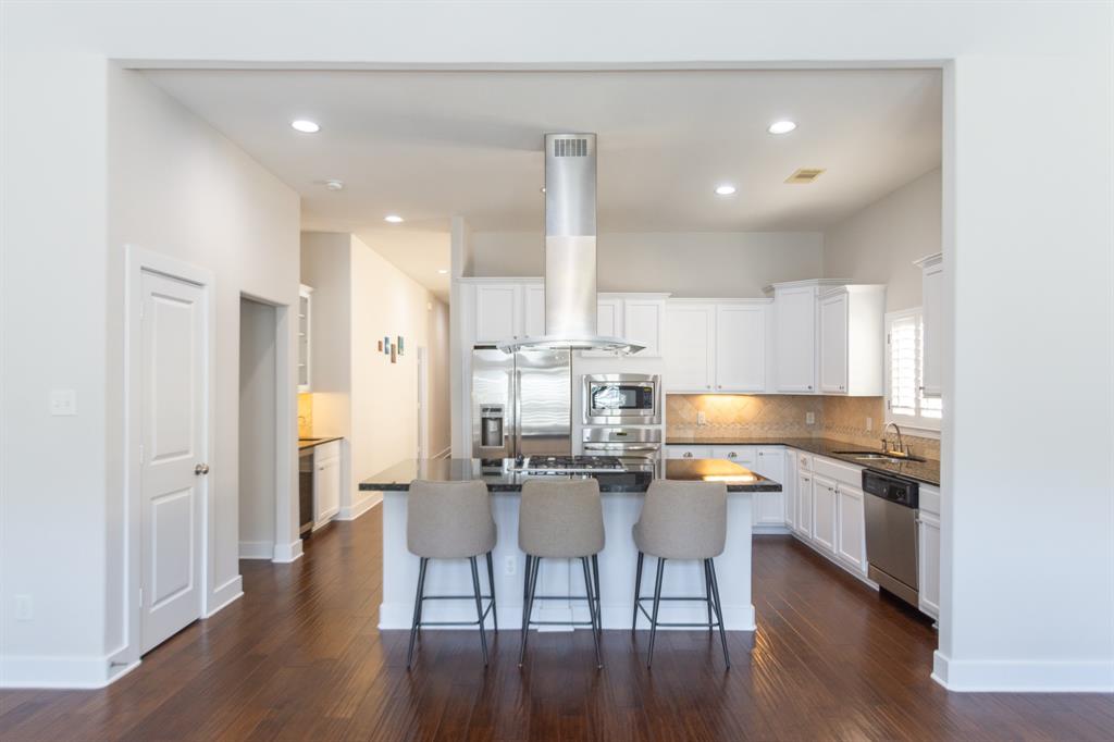 a kitchen with stainless steel appliances kitchen island granite countertop a dining table chairs and white cabinets