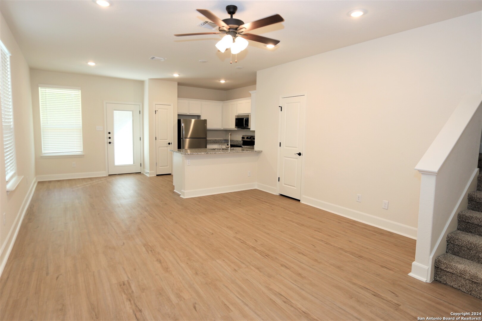 a view of a kitchen with wooden floor and a ceiling fan