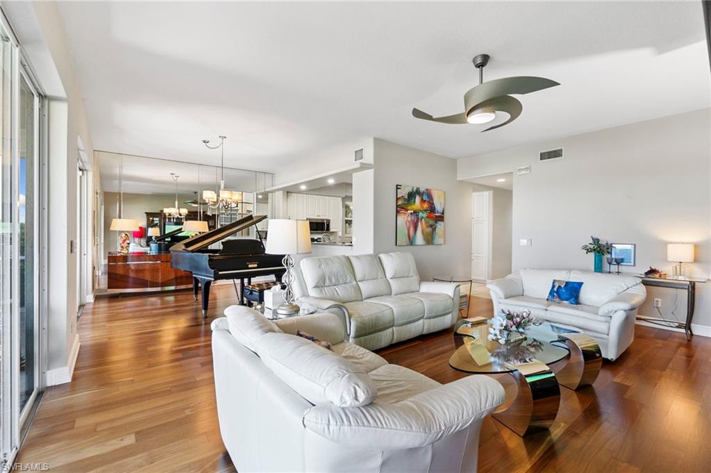 Living room with hardwood / wood-style floors and ceiling fan with notable chandelier