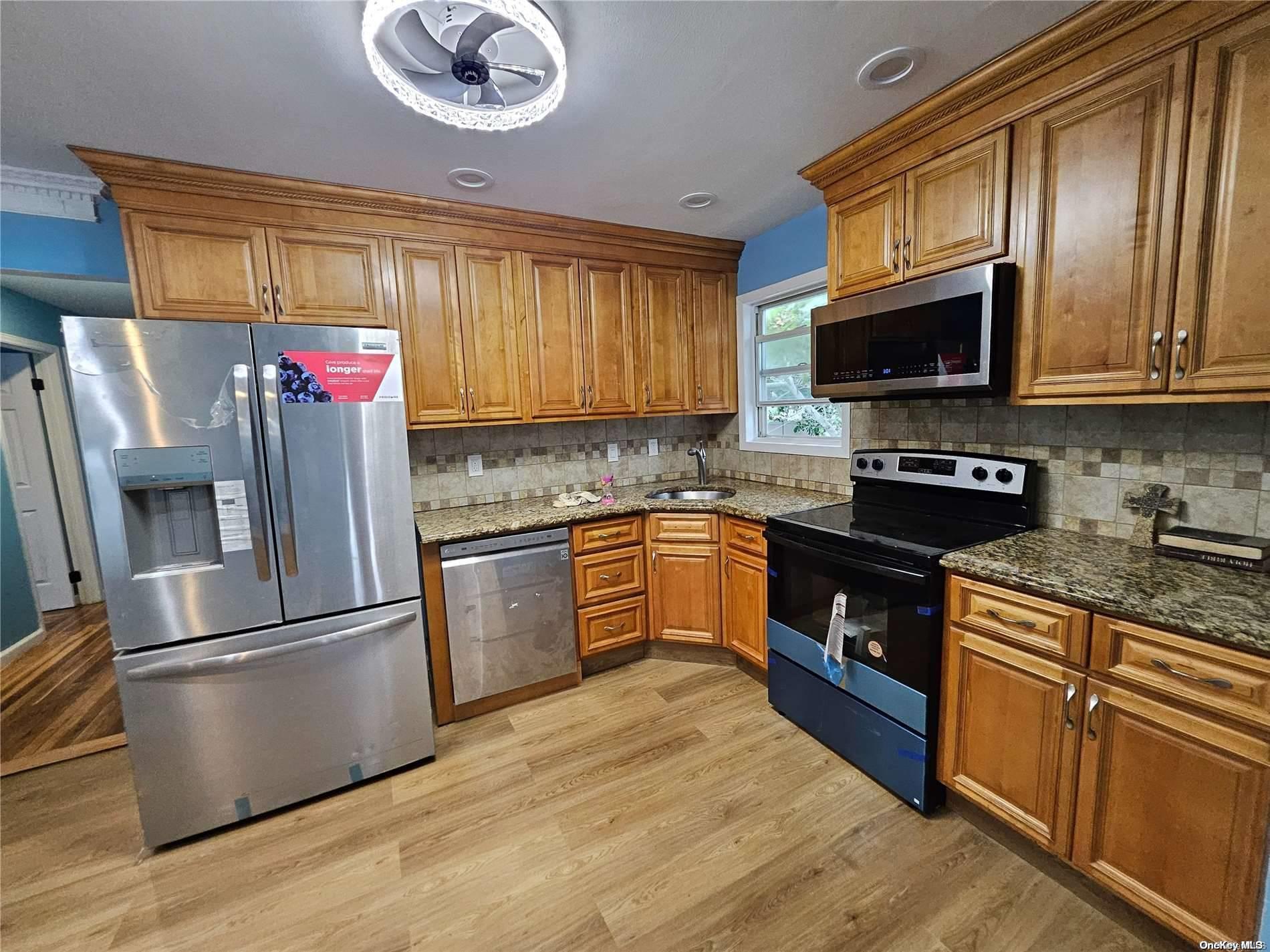 a kitchen with stainless steel appliances granite countertop a refrigerator sink and microwave