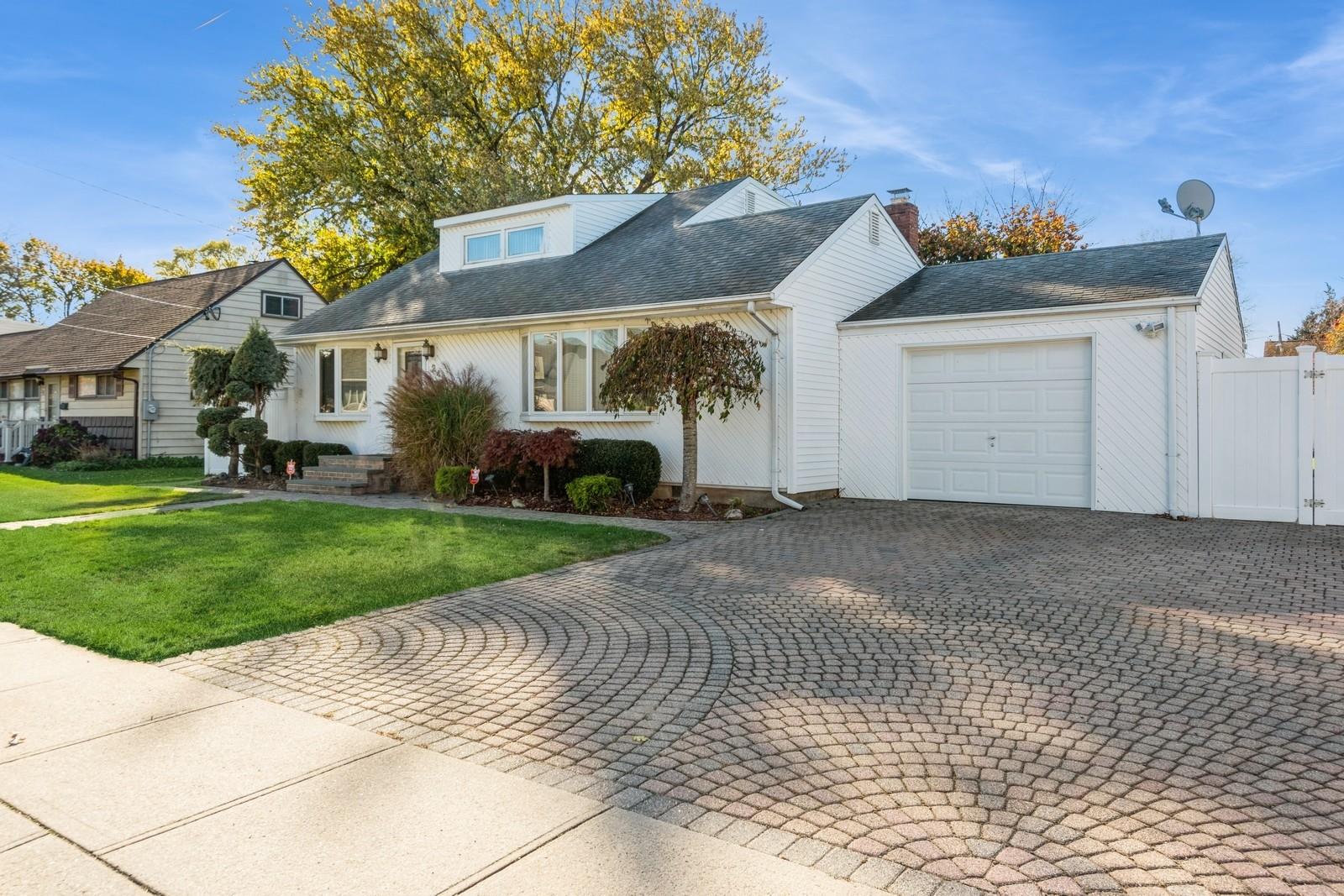 View of front facade featuring a front yard and a garage