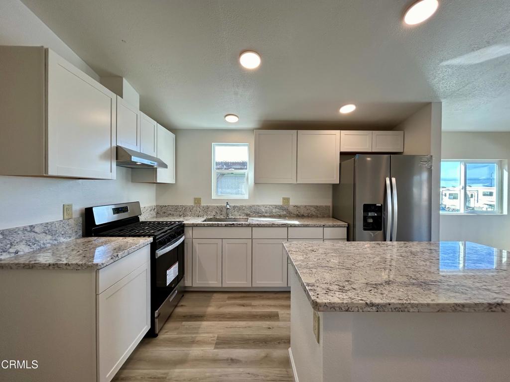 a kitchen with stainless steel appliances granite countertop a sink stove and refrigerator