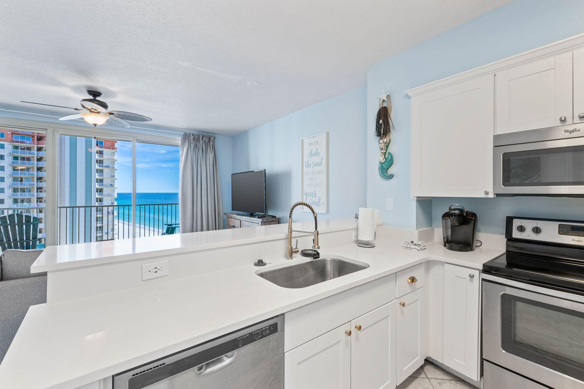 a kitchen with stainless steel appliances a sink a stove and a granite counter tops with white cabinets