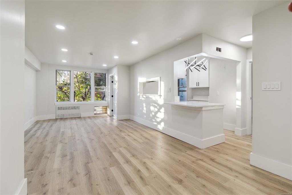 Unfurnished living room with a chandelier, radiator heating unit, and light hardwood / wood-style flooring