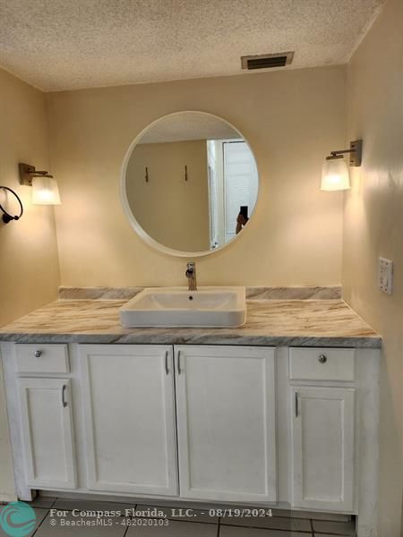 a bathroom with a granite countertop sink and a mirror