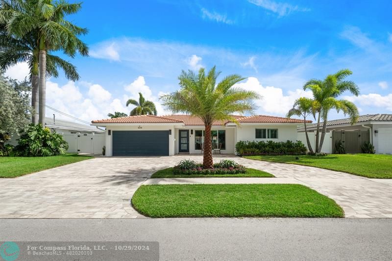 a front view of a house with a garden and palm trees