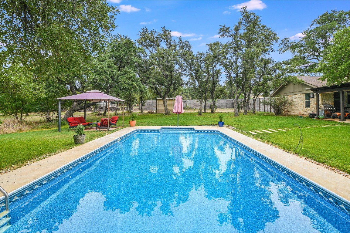 a view of swimming pool with lawn chairs and large trees