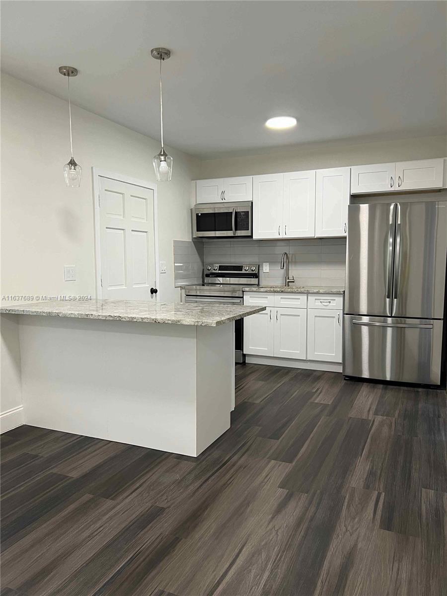 a kitchen with kitchen island granite countertop a sink cabinets and stainless steel appliances