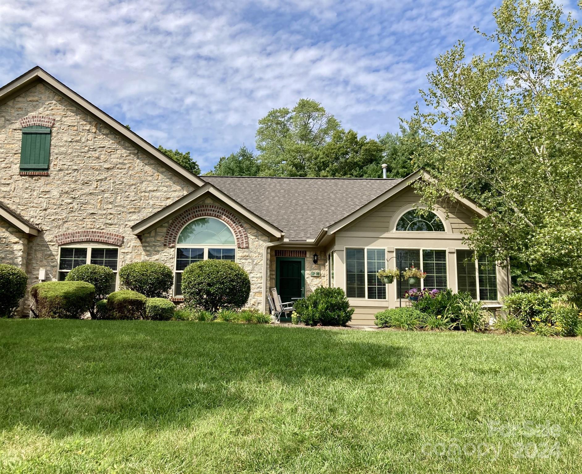 a front view of a house with a yard and green space