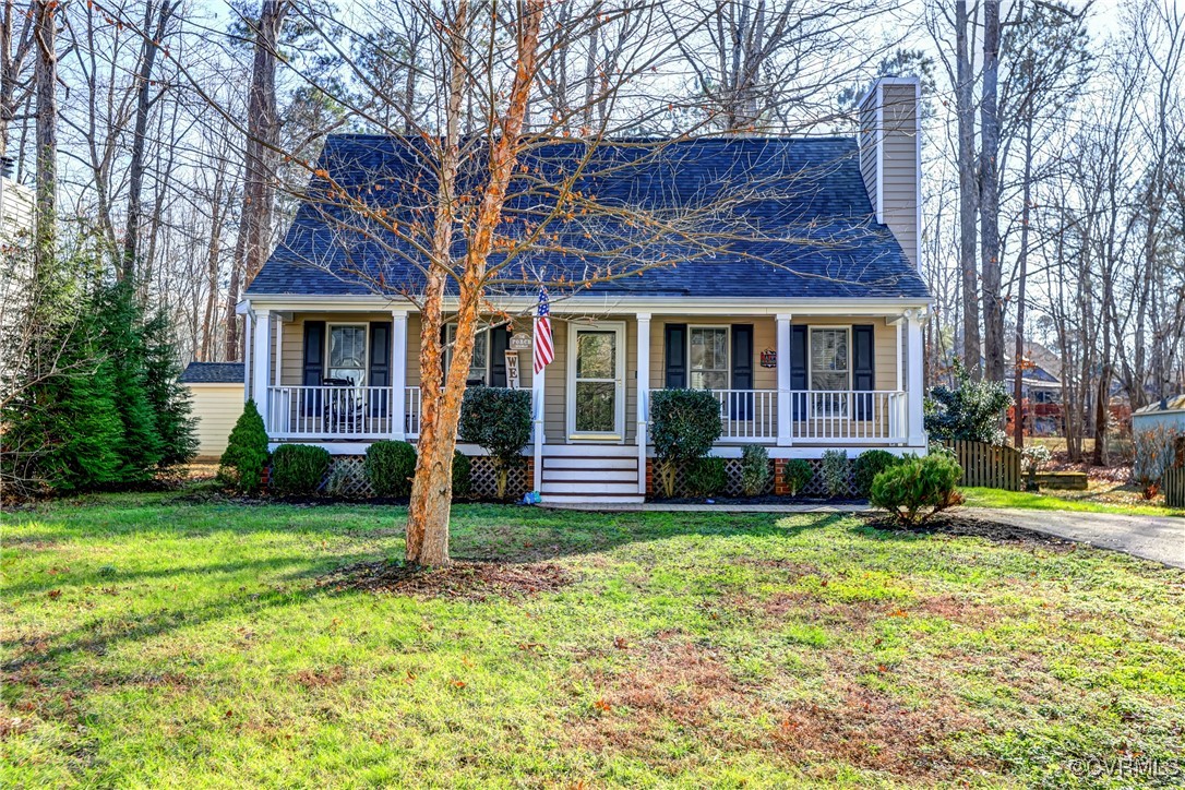 a view of a brick house with a yard plants and large tree