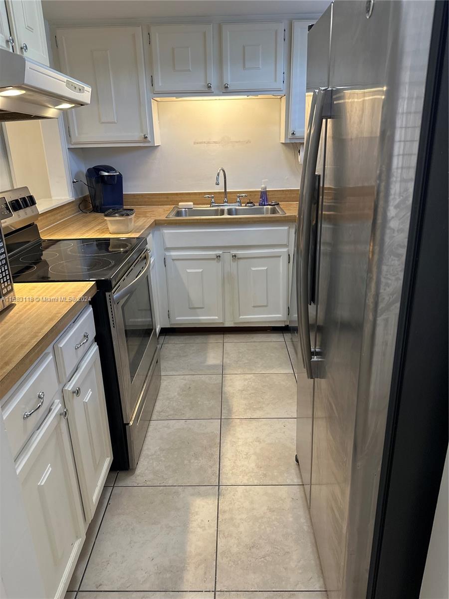 a kitchen with a sink a refrigerator a window and cabinets