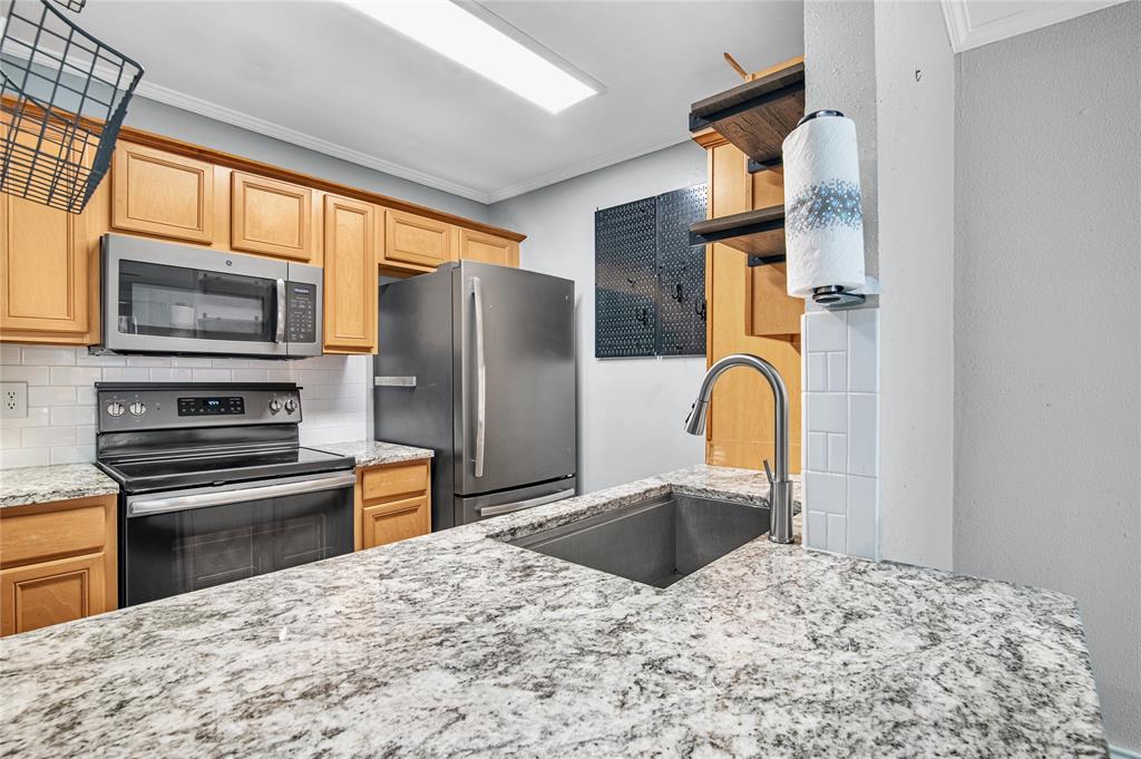 a kitchen with stainless steel appliances kitchen island granite countertop a refrigerator stove top oven and sink