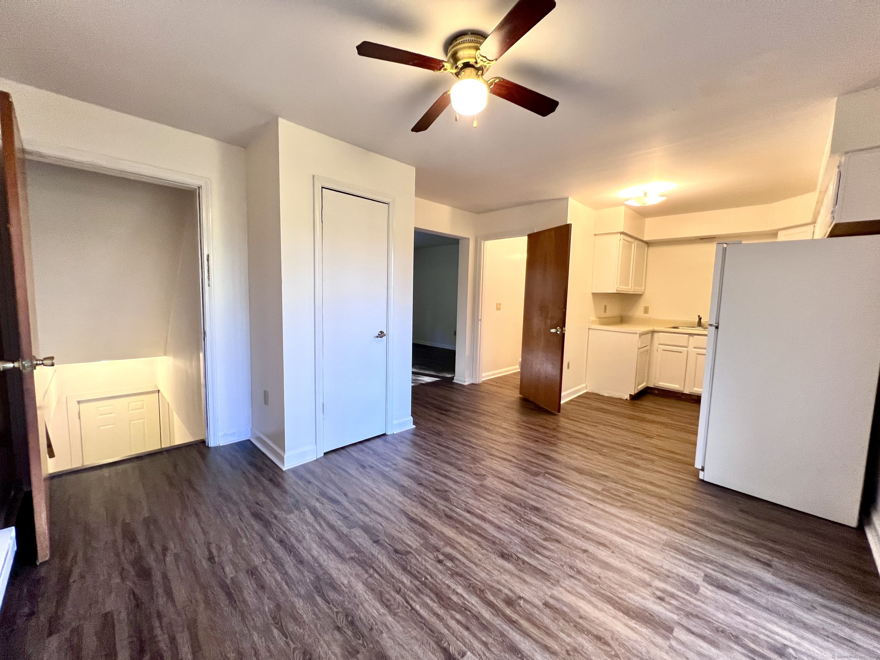 a view of empty room with wooden floor and fan