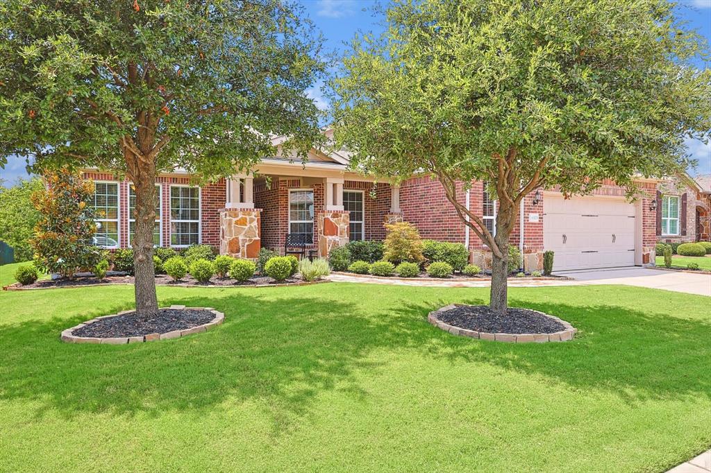 a front view of a house with a garden and trees